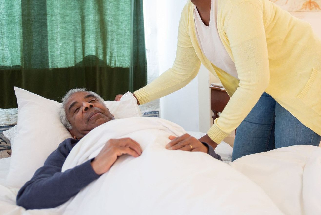 A woman tending to an elderly man in a bright and warm bedroom, symbolizing care and family support.